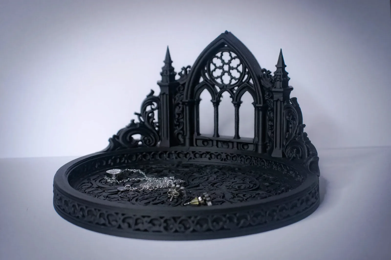 Black 3D-printed gothic cathedral jewelry stand with a rose-window arch, spires and a filigree tray holding silver jewelry
