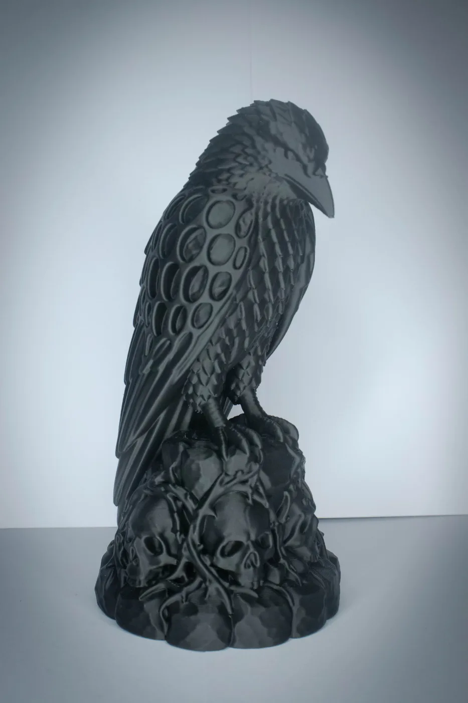 Black 3D-printed gothic raven figurine perched on a base of carved skulls