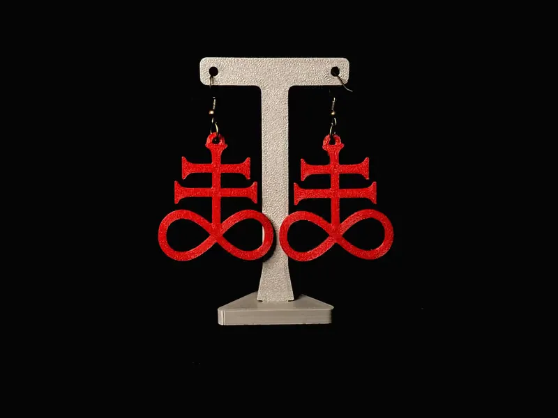 Red 3D-printed Leviathan cross earrings hanging on a display stand