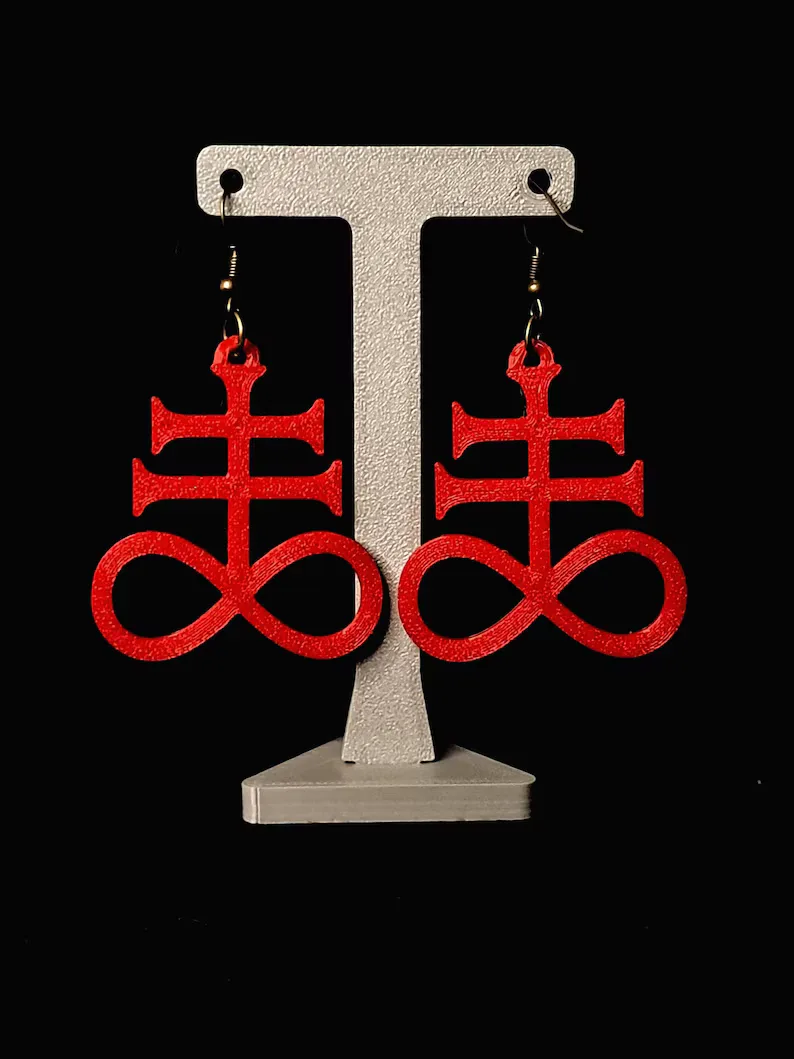Red 3D-printed Leviathan cross earrings hanging on a display stand